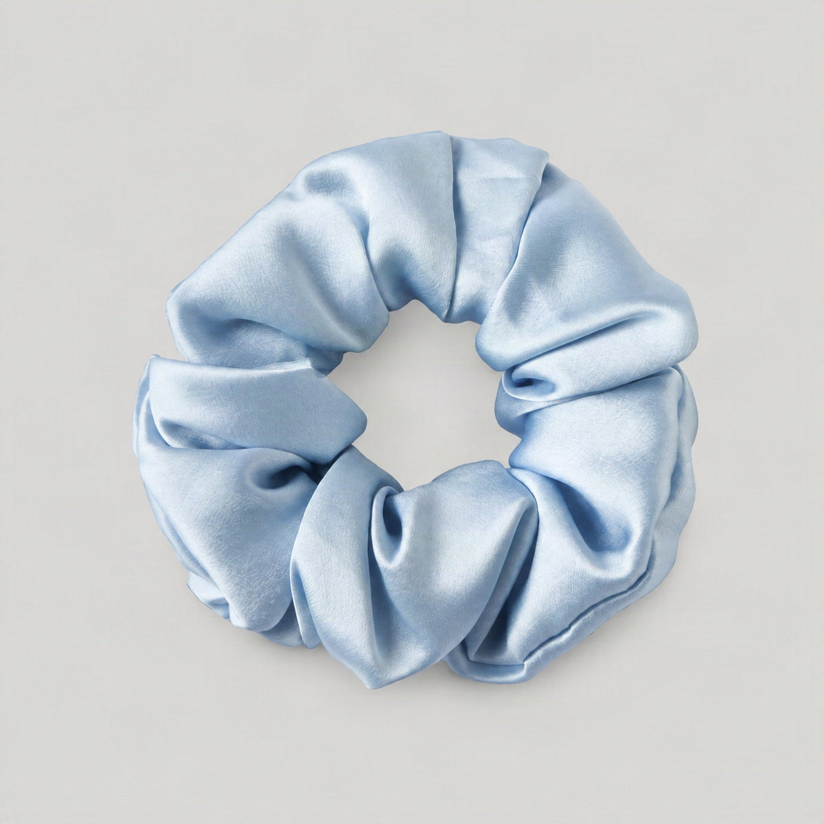 SuuSilk 16 Momme ruffled mulberry silk scrunchie in soft cream draped on a marble surface, gentle hair accessory for daily we