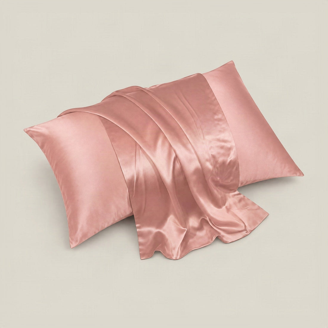 Light pink rectangular silk pillowcase with a small red, beige, and green floral pattern on an off-white background.