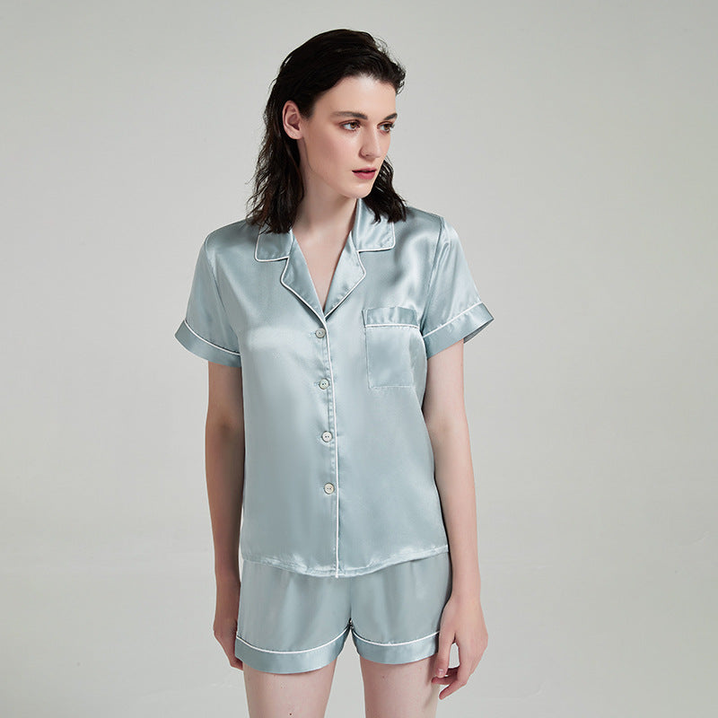 A woman in a long-sleeve mulberry silk pajama set with watercolor blue-and-pink Oasis Walk print, photographed against a neutral studio background.