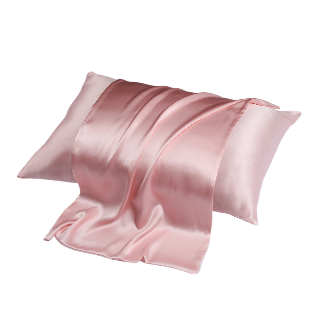 A pair of pink silk pillowcases, one partially draped over the other, against a white background