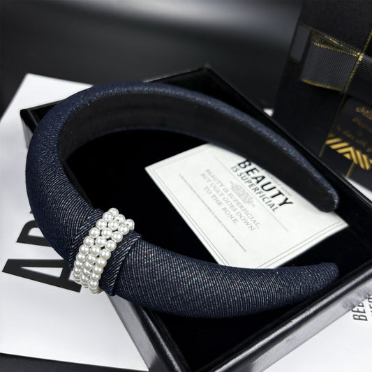 Navy blue denim-textured headband with triple-row pearl embellishment on a black box