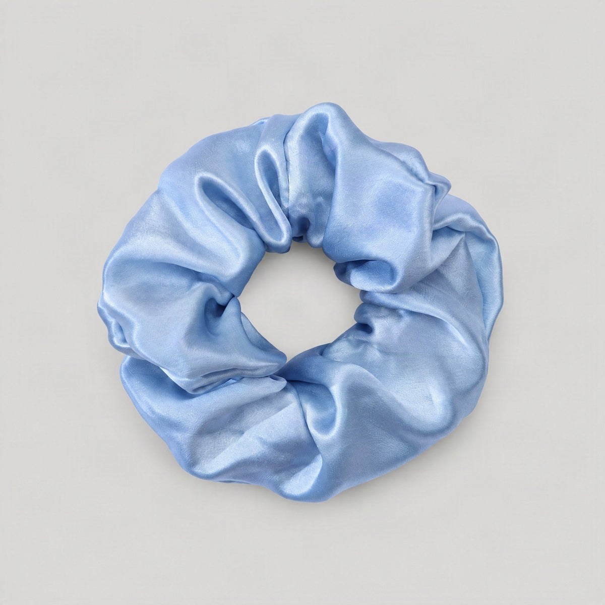 Soft champagne silk scrunchie in flowing fabric, displayed against a neutral background for gentle everyday hair styl