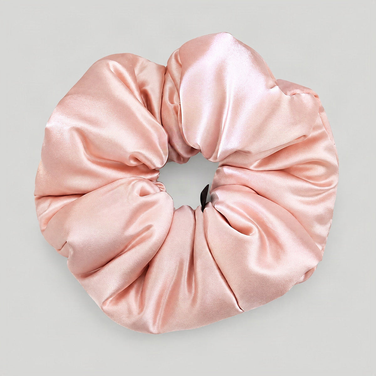 Mulberry silk scrunchie in soft pastel shade resting on a linen surface, gentle everyday hair accessory displayed in natural 