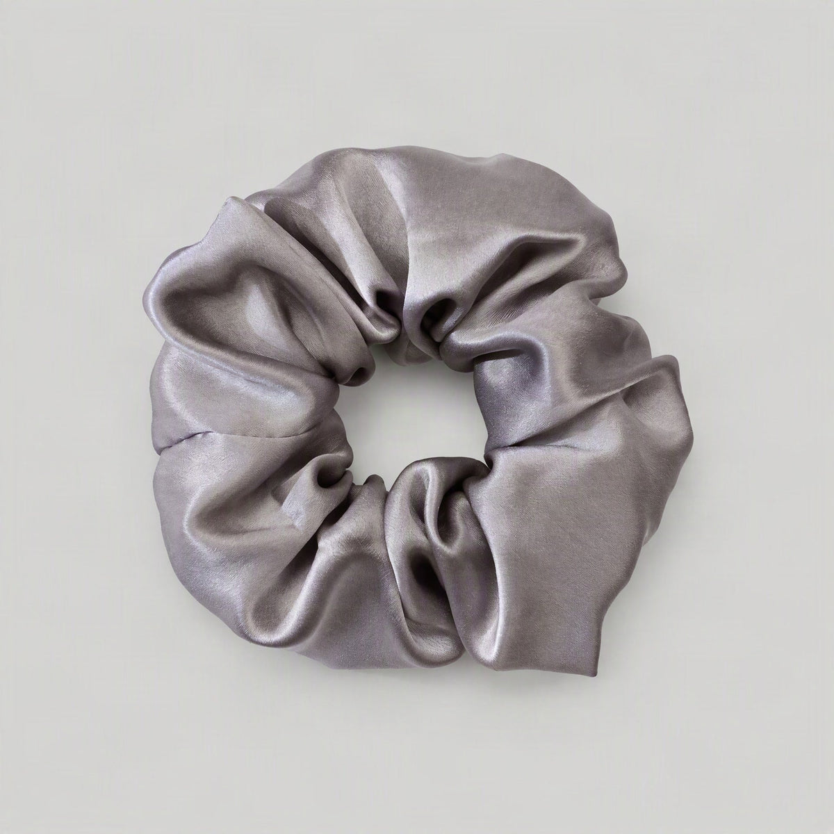 SuuSilk mulberry silk scrunchie in soft blush pink, gently scrunched on a marble surface for an elegant lifestyle dis