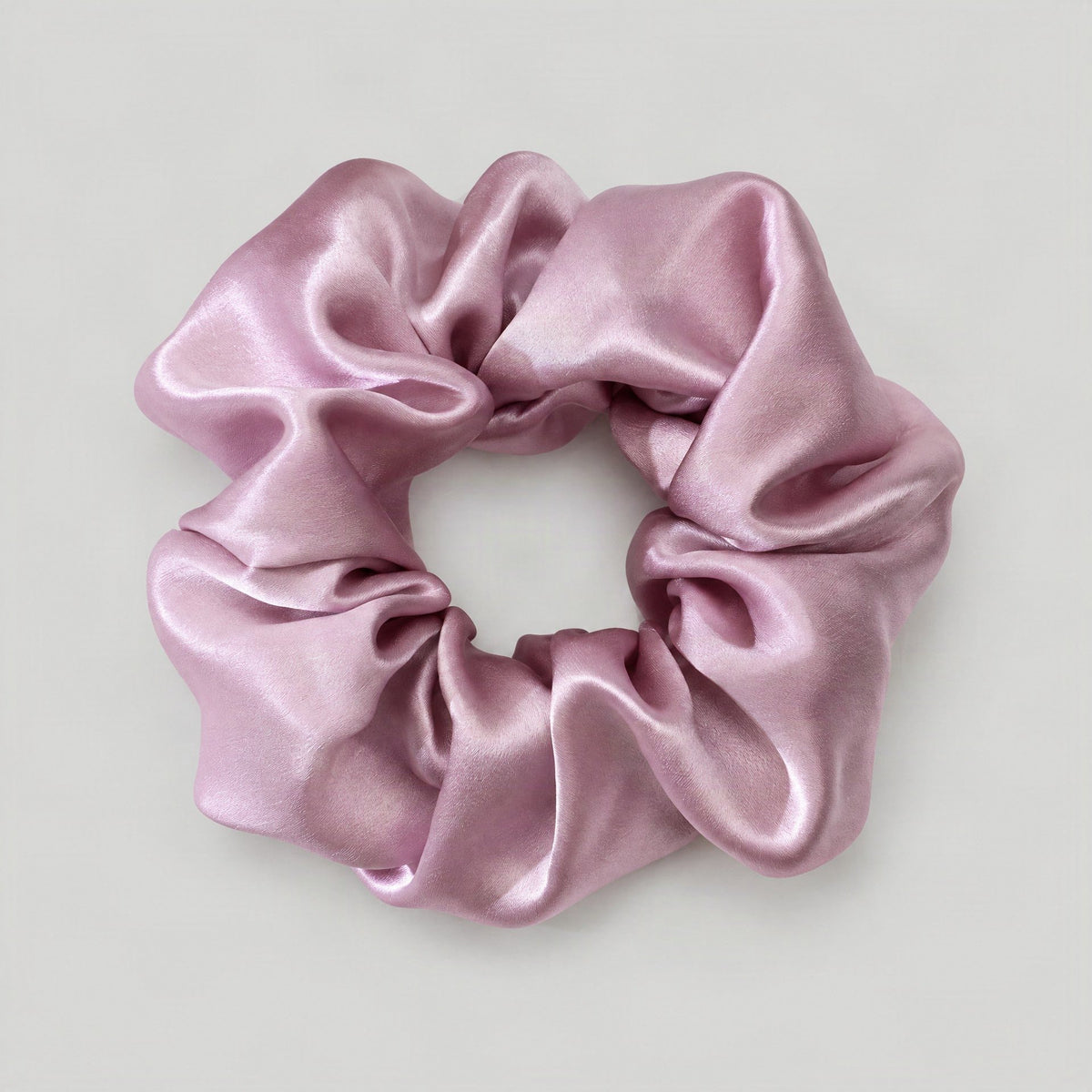 SuuSilk mulberry silk scrunchie in soft blush pink, gently scrunched around a loose hair tie on a marble vanity