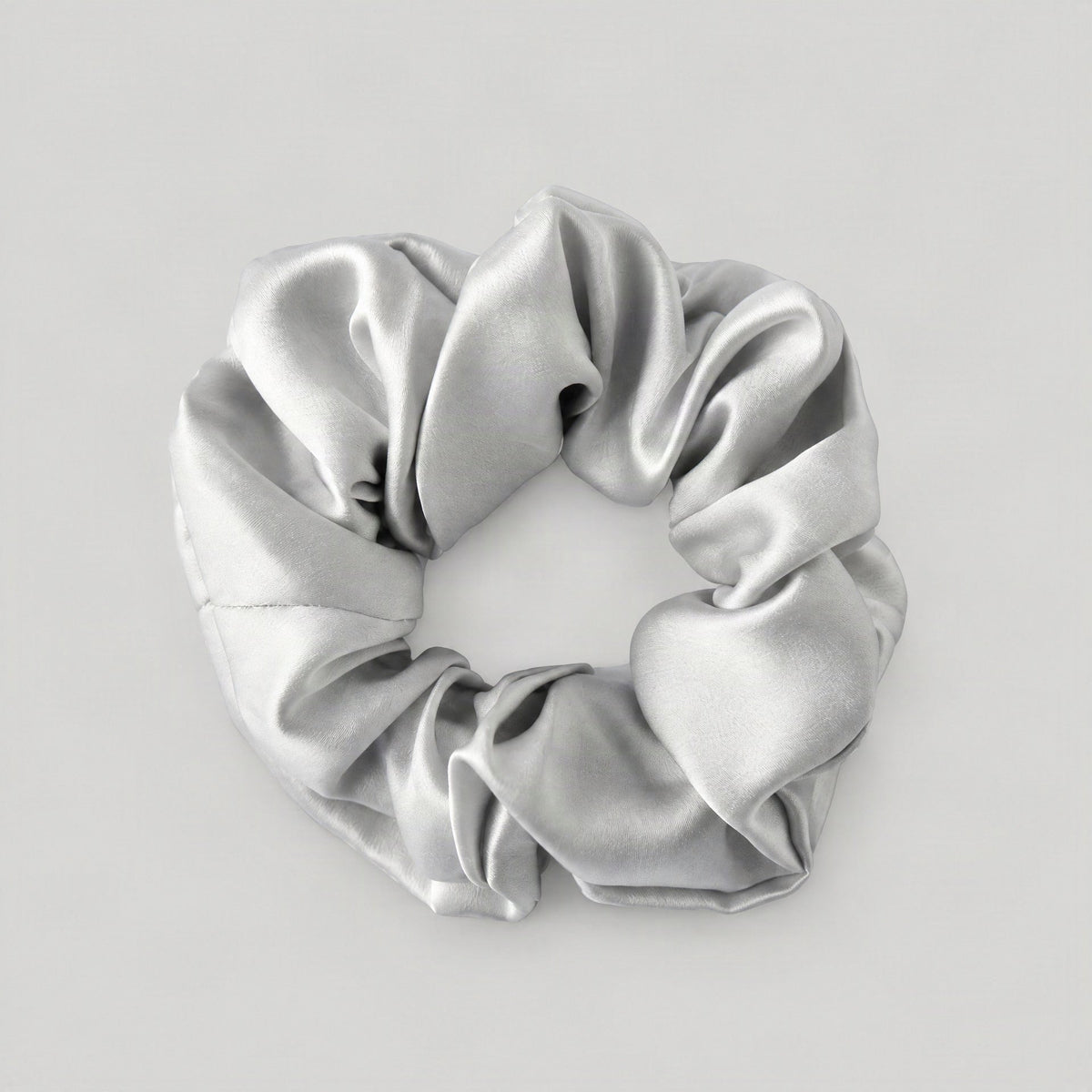 SuuSilk 16 Momme ruffled mulberry silk scrunchie in soft blush pink, styled on a marble vanity with delicate dried florals
