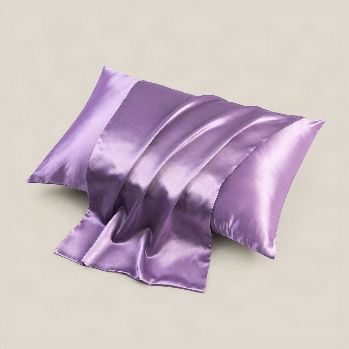 Champagne-colored SuuSilk 19 momme mulberry silk pillowcase with hidden zipper neatly arranged on a soft beige bed setting.