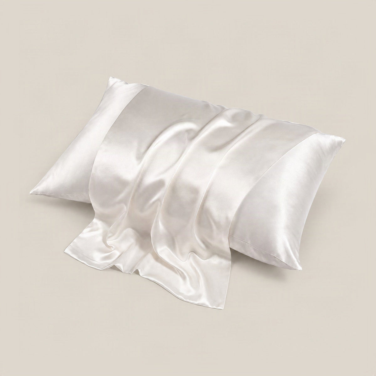 Lifestyle shot of the 22 Momme matte silk pillowcase in soft blush pink, draped on a bed with natural lighting highlighting i