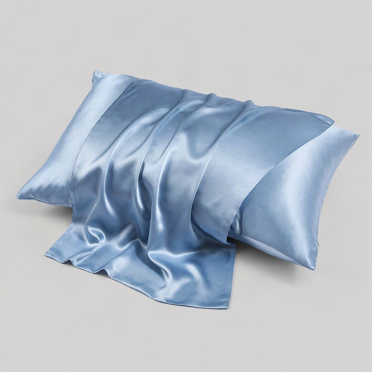 Light blue silk envelope pillowcase on neutral bedding, highlighting the matte mulberry silk finish and hidden closure detail.