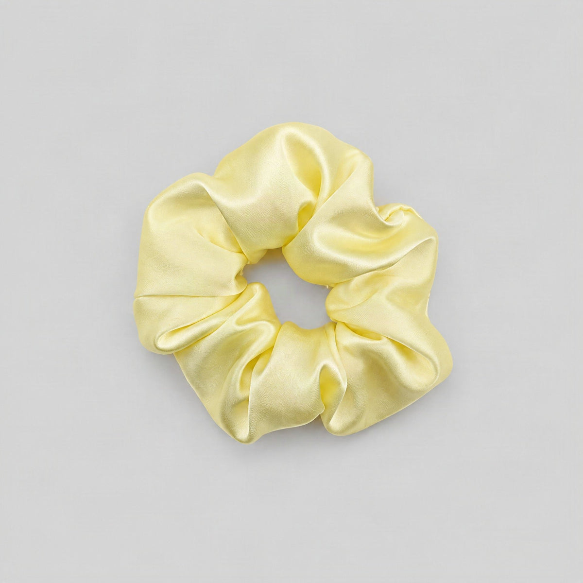 SuuSilk 30 Momme mulberry silk scrunchie in soft champagne tone, gently wrapped around a loose hair tie on a neutral linen su