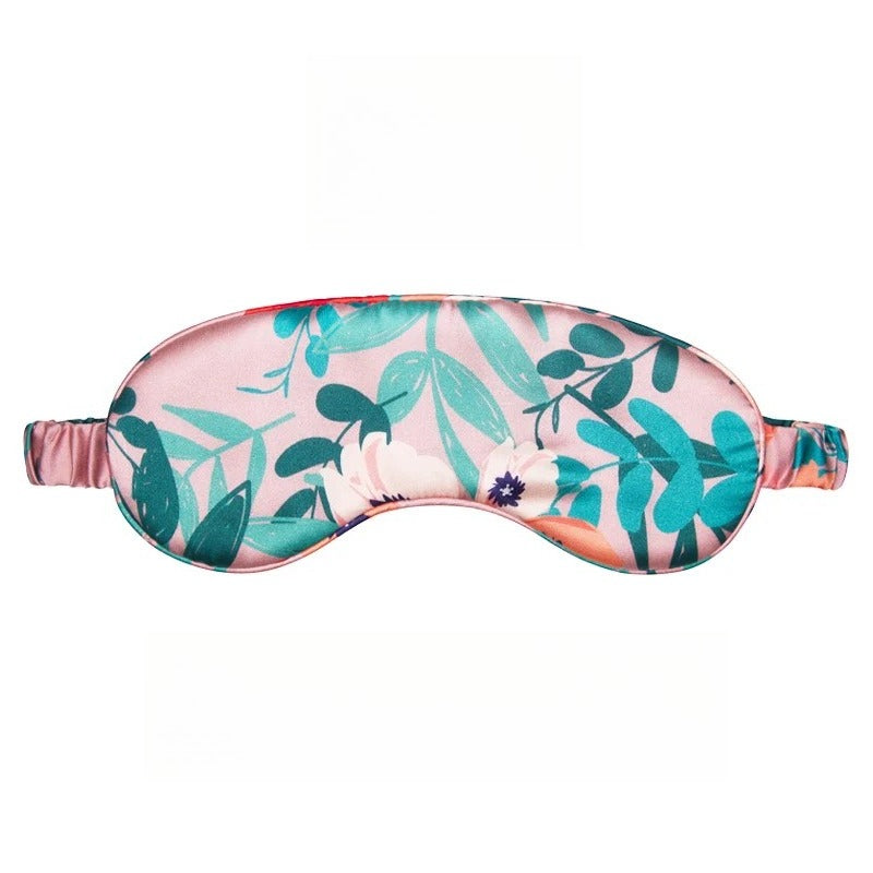 SUUMEE mulberry silk sleep eye mask laid on soft bedding in a dimly lit bedroom setting