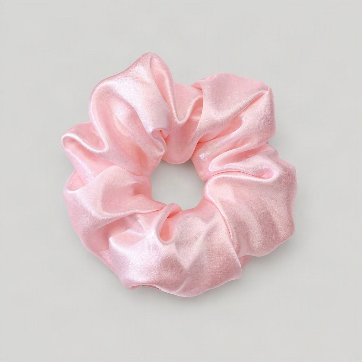 SuuSilk mulberry silk scrunchie in soft pink, draped on a marble surface to highlight its delicate textu
