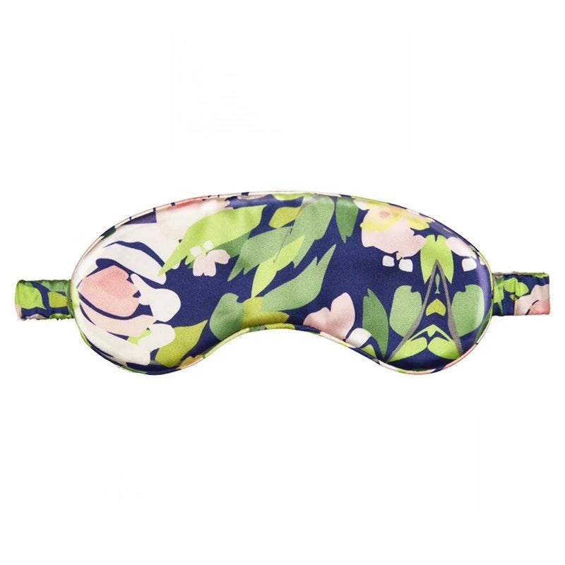 SUUMEE mulberry silk sleep eye mask in soft pink, shown resting on a bedside table for travel and sleep use