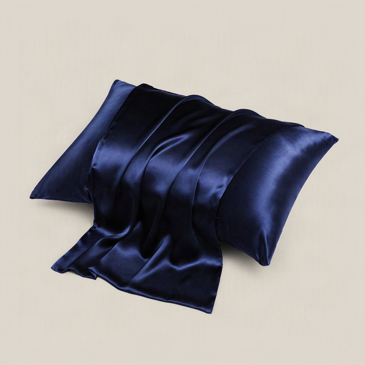 SuuSilk 16 Momme mulberry silk pillowcase draped on bed, soft light highlighting smooth lustrous fabric and hidden closure