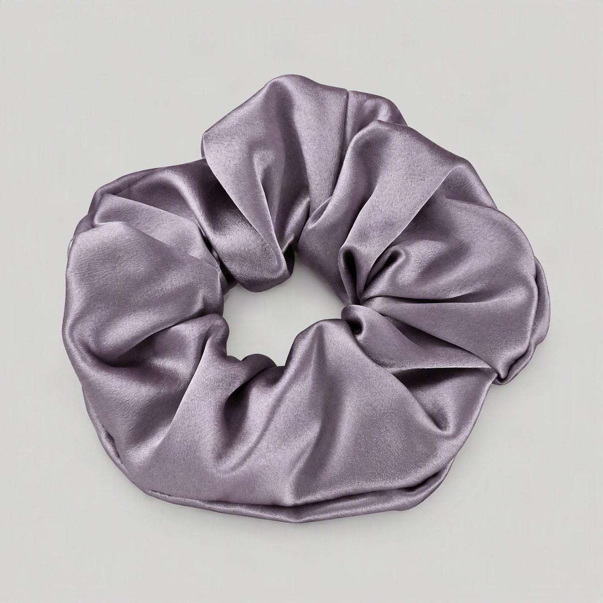 SuuSilk 30 Momme Mulberry Silk Scrunchie in soft neutral tone, gently wrapped around a loose hair tie on a light surface