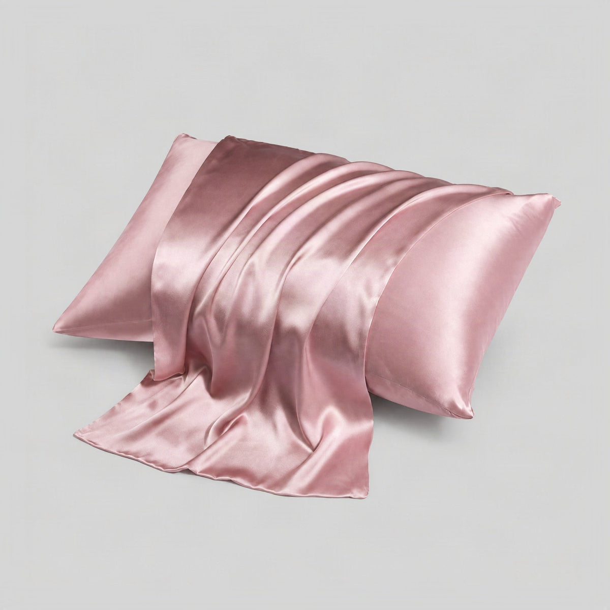 SuuSilk 16 momme mulberry silk envelope pillowcase in soft blush tone, draped on a bed with natural morning light highlightin