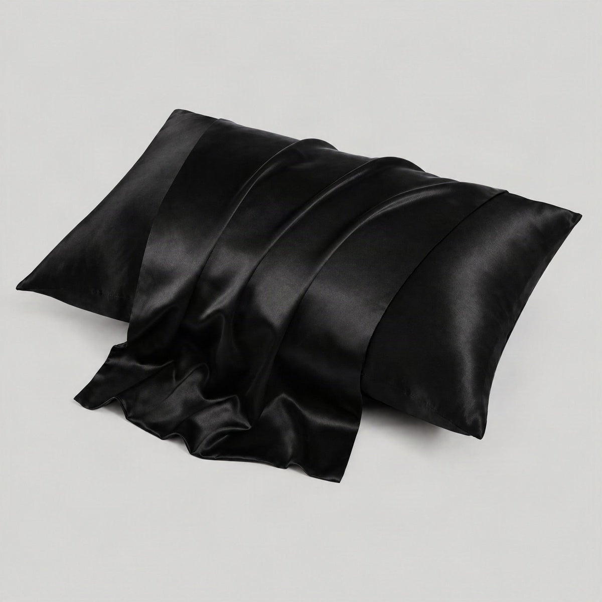 Black 22 Momme silk pillowcase with hidden envelope closure draped elegantly on a neutral linen bed setting