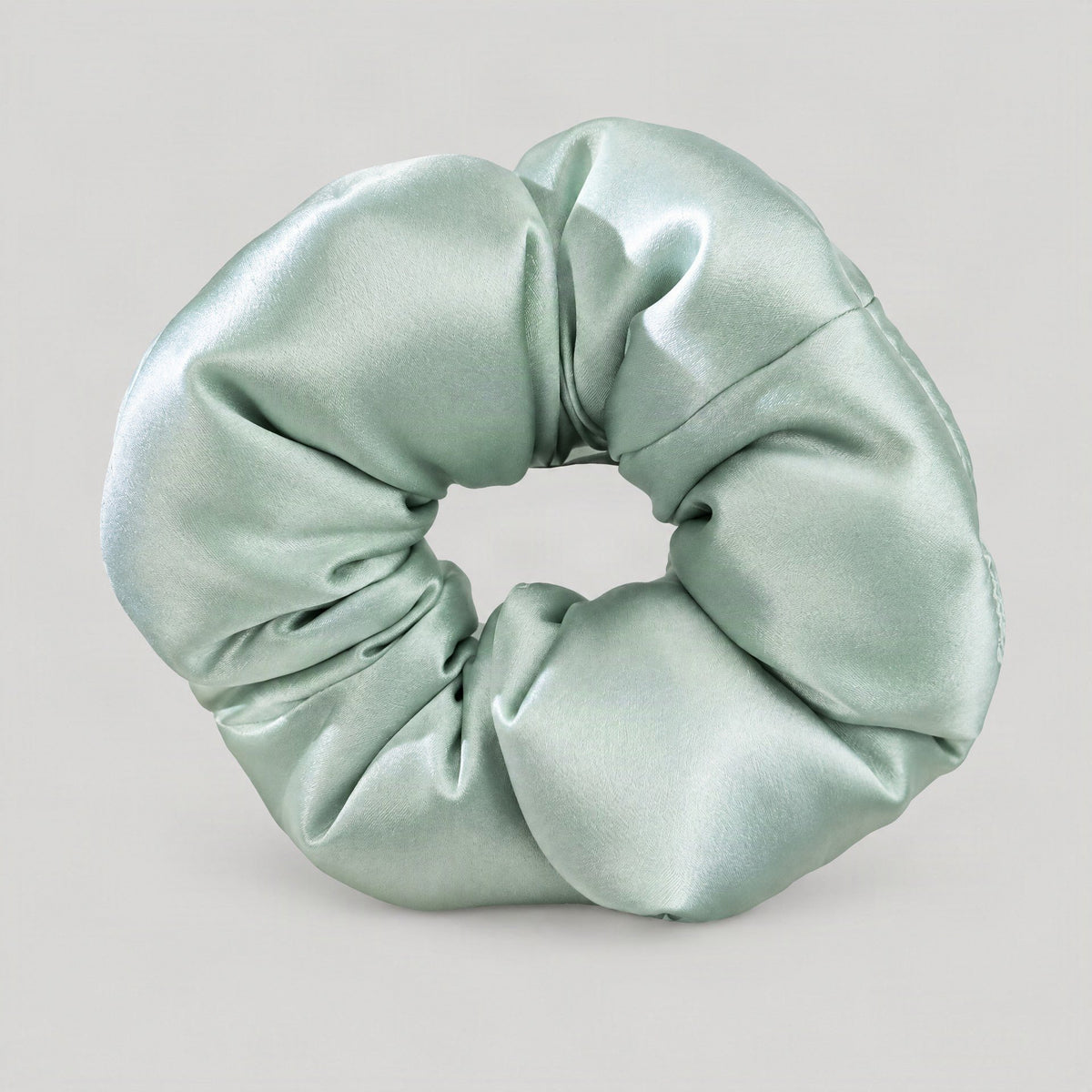 SuuSilk 30 Momme Mulberry silk padded scrunchie in soft beige, resting on a marble surface for an elegant lifestyle display.