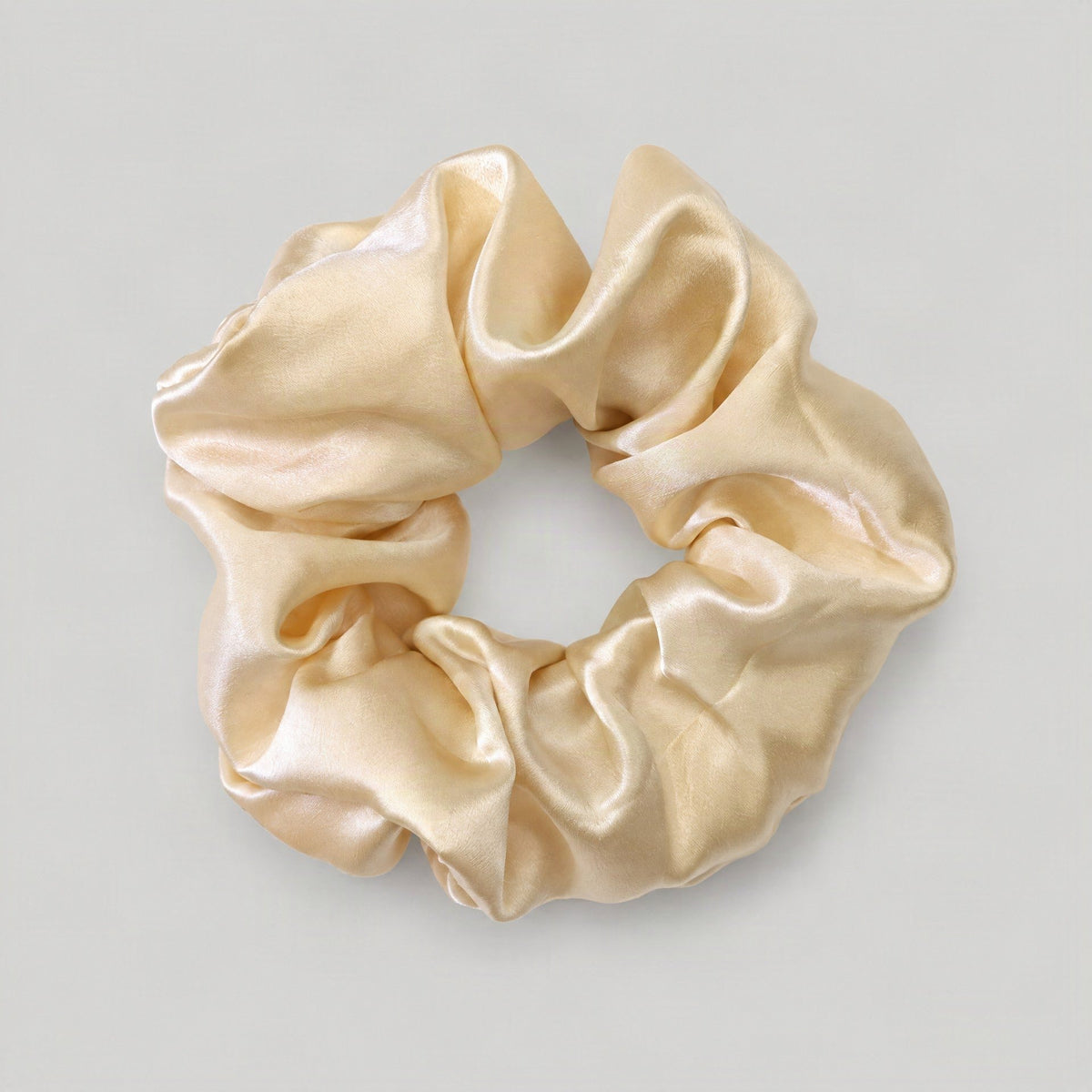 Soft pink SuuSilk mulberry silk scrunchie resting on a white marble surface, showcasing its gentle textu