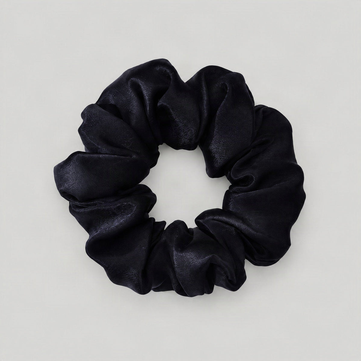 SuuSilk Mulberry silk scrunchie in soft pink resting on a white marble surface, gentle everyday hair accessory