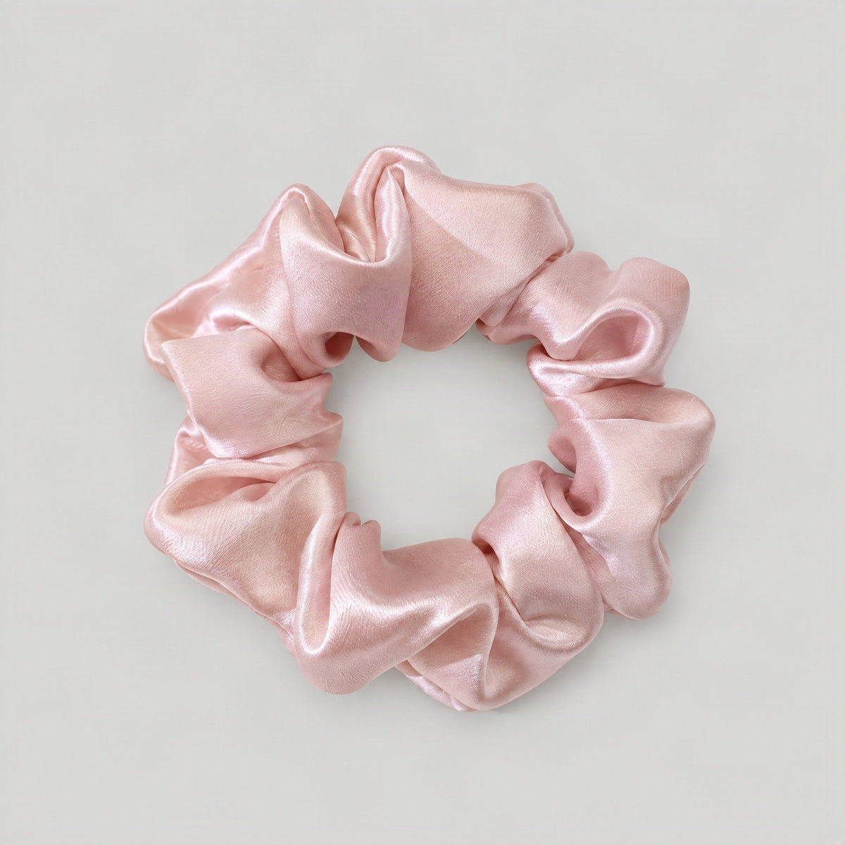 SuuSilk mulberry silk scrunchie in soft pastel color resting on a light marble surface with delicate fabric folds vis
