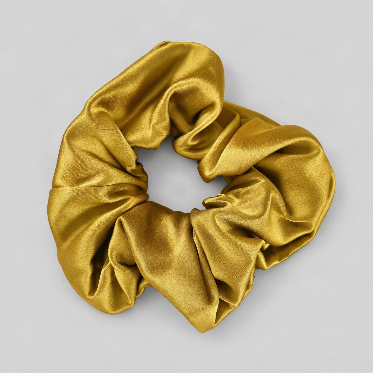 SuuSilk 30 Momme mulberry silk scrunchie in soft beige, gently gathered on a marble surface showing its smooth lustrous textu