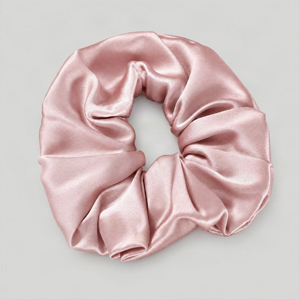 SuuSilk 30 Momme mulberry silk scrunchie in soft beige, gently wrapped around a sleek ponytail on a marble surface