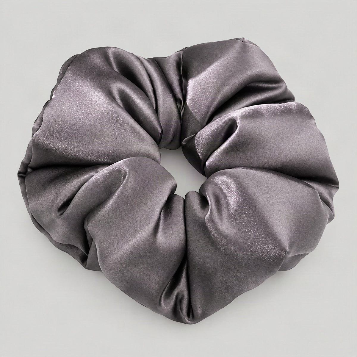 White 30 Momme Mulberry silk padded scrunchie resting on a soft fabric surface for hair styling.