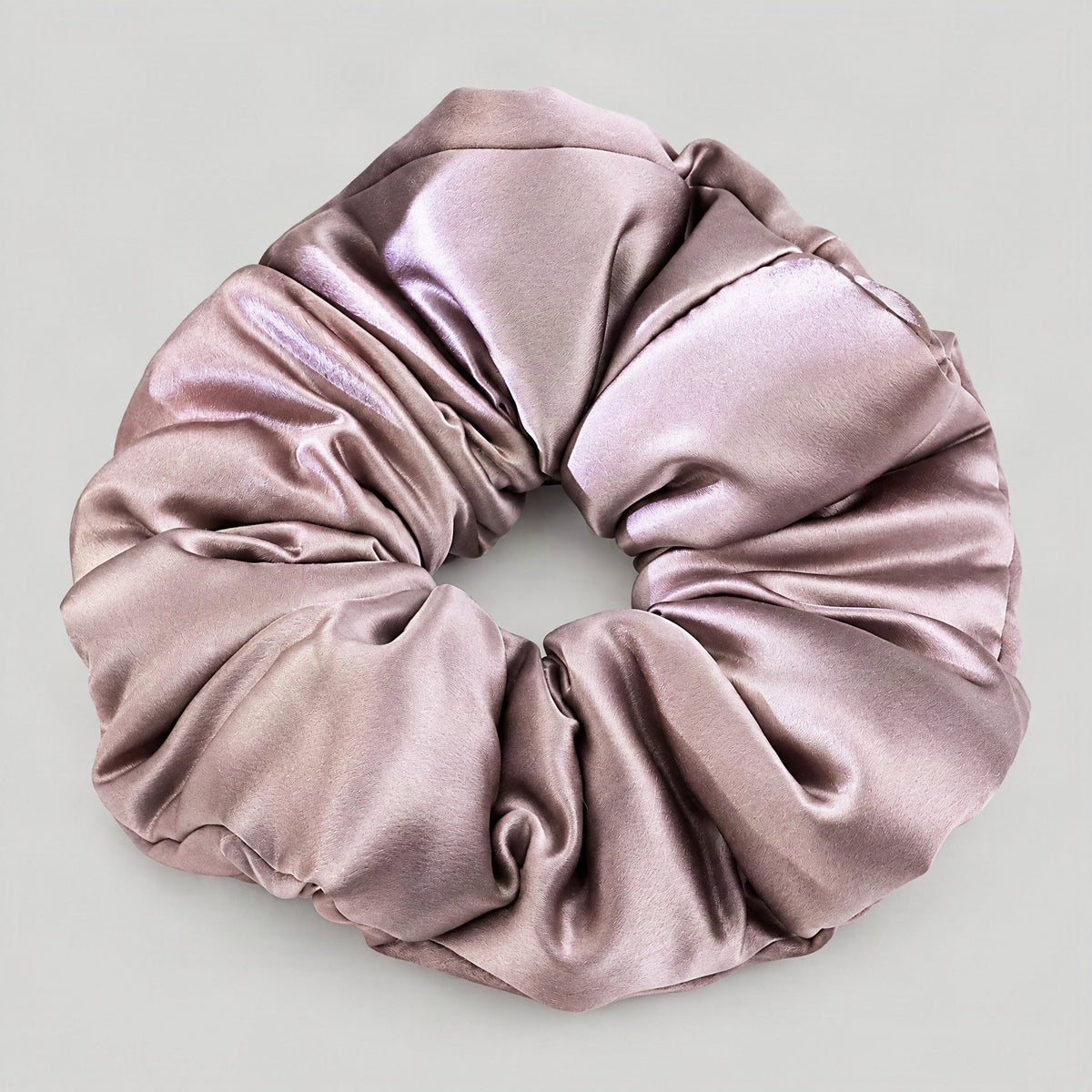SuuSilk 30 Momme mulberry silk scrunchie in soft pink, displayed on a marble surface to highlight its padded sheen