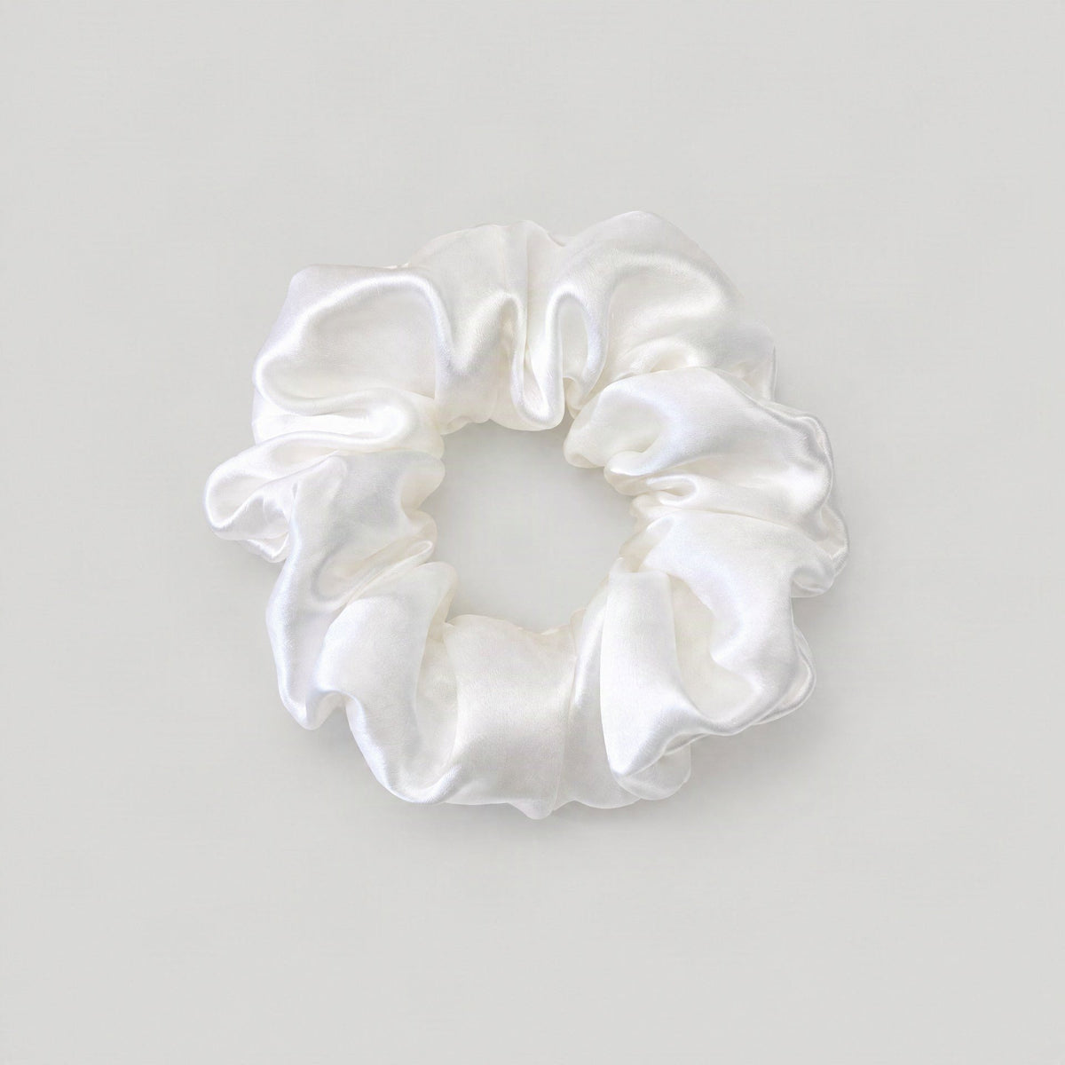 SuuSilk mulberry silk scrunchie resting on a soft beige surface, showcasing its gentle texture