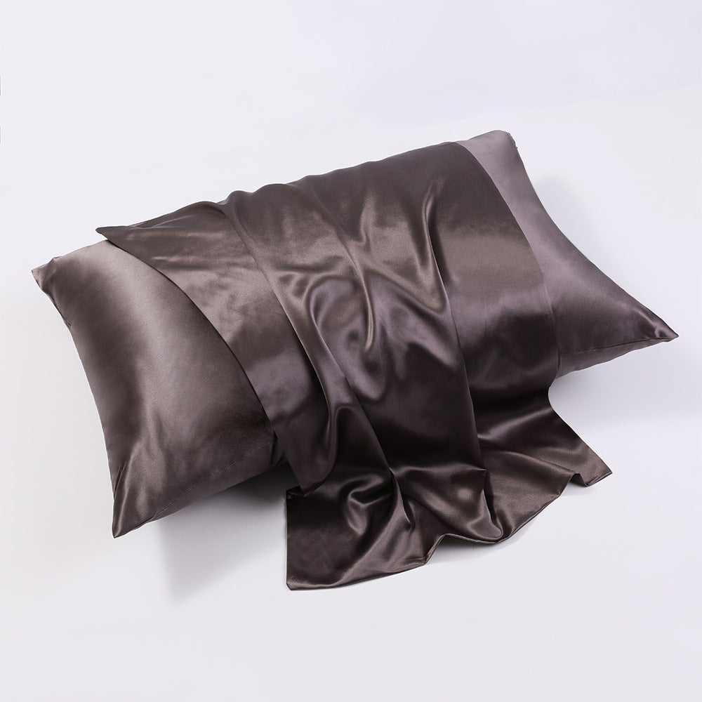 Dark gray silk pillowcase draped over pillow in soft light