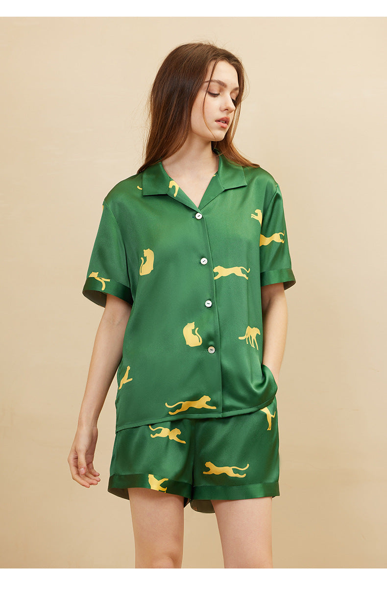 Woman wearing dark green silk pajama set in bedroom setting