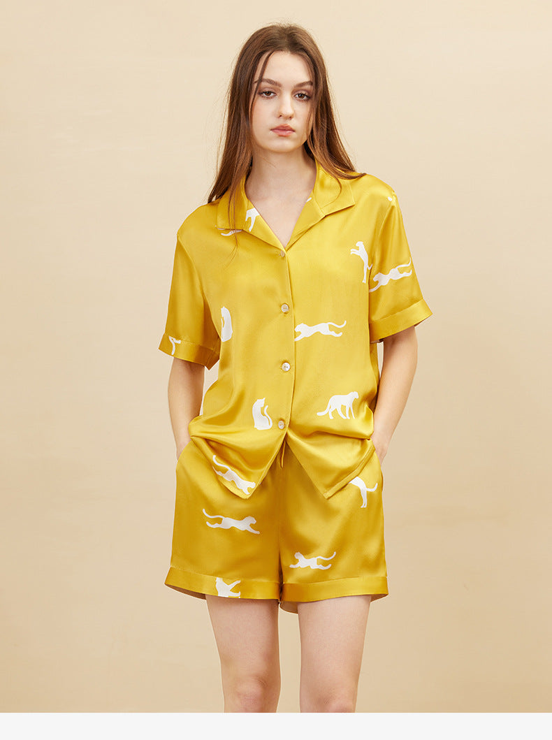 Lifestyle shot of woman wearing gold silk pajama set lounging on sofa