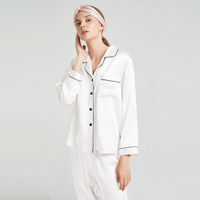 Close-up of white silk pajama top with contrast piping detail