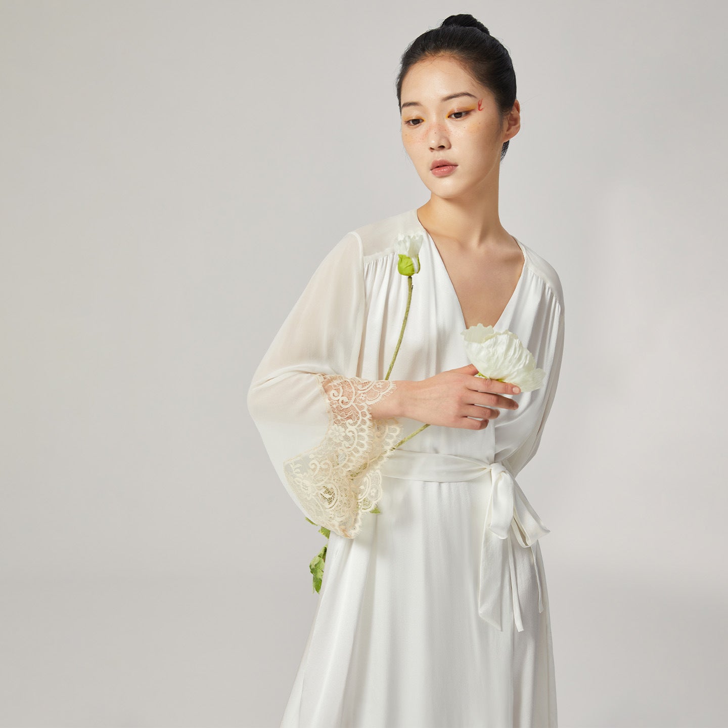Model holding white poppy flower wearing silk loungewear robe