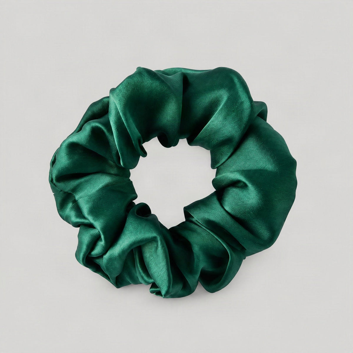 SuuSilk 16 Momme ruffled mulberry silk scrunchie draped on linen, showcasing its lustrous sheen and gentle fabric texture