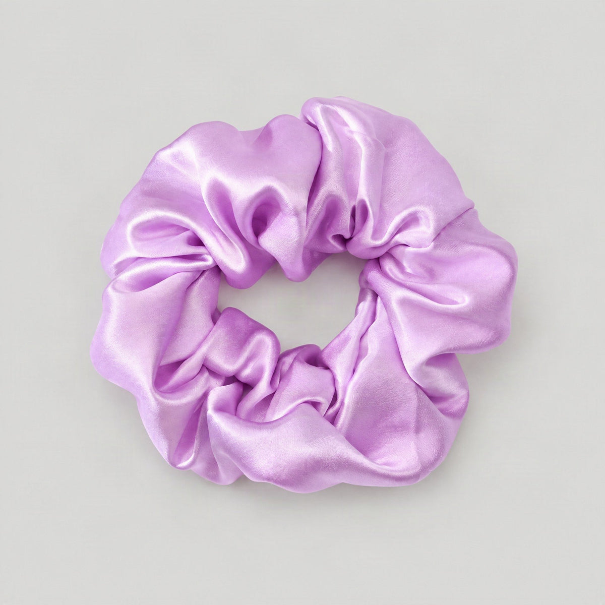 SuuSilk mulberry silk scrunchie in soft pink resting on a cream linen surface, styled for everyday wear.