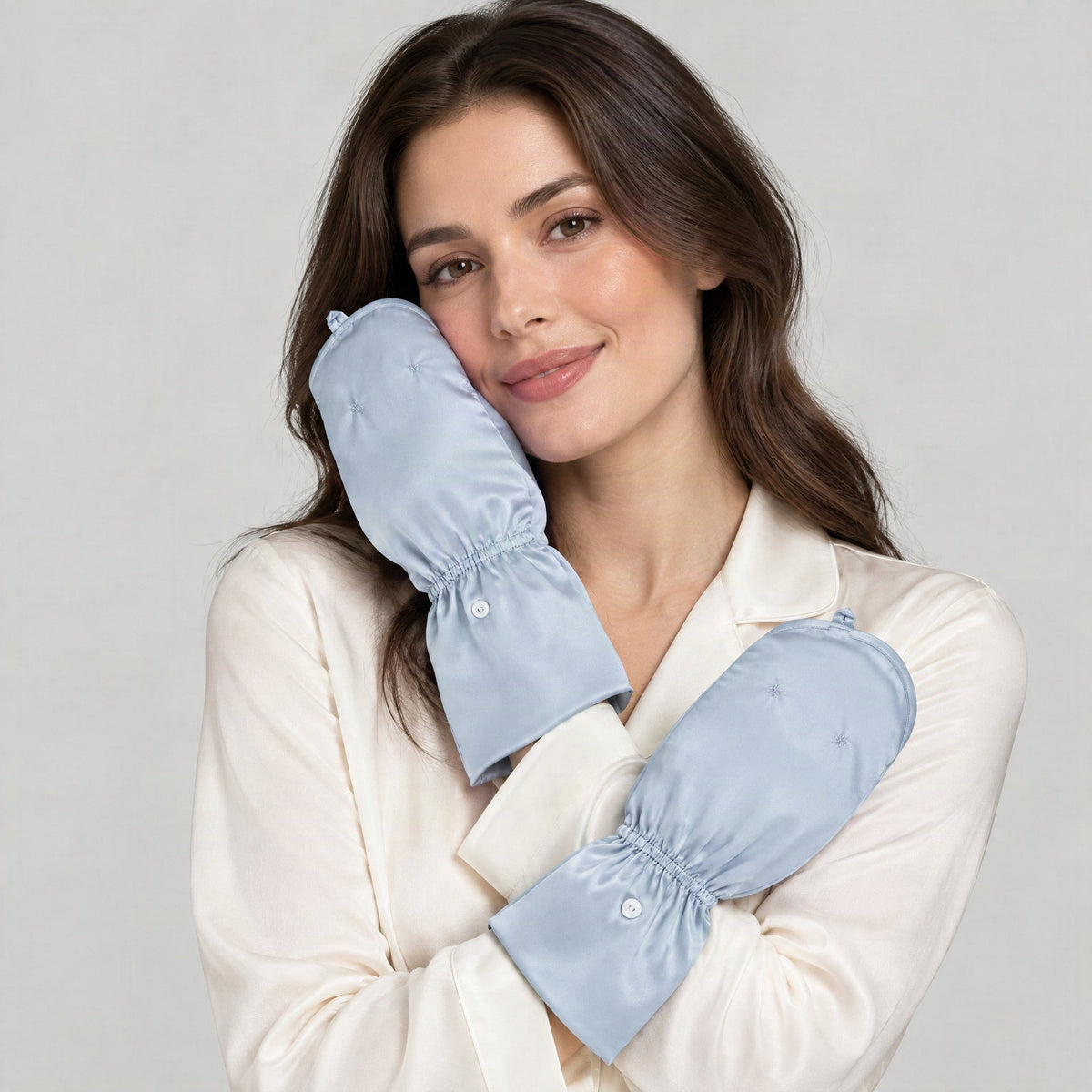 Model holding a pair of light blue mulberry silk UV arm sleeves with hand covers up to her face