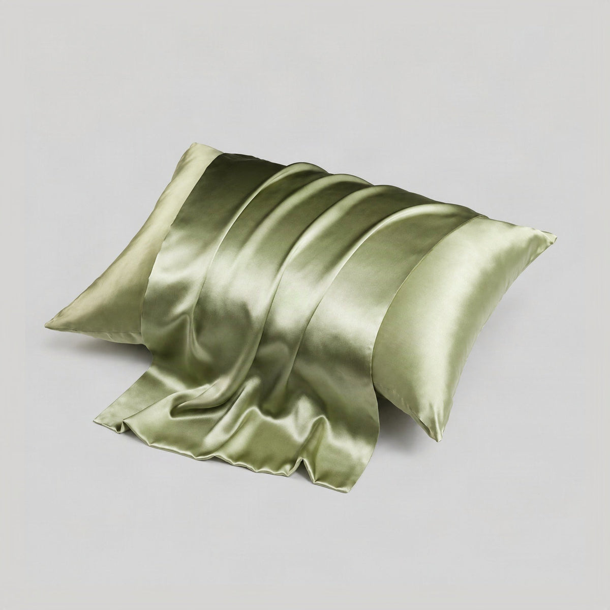SuuSilk mulberry silk envelope pillowcase in soft pastel color draped on a bed, showcasing smooth double-sided sheen and hidd