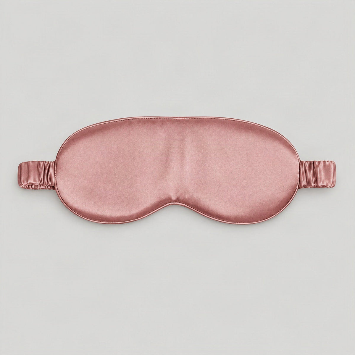 SuuSilk 19 Momme 3D Contoured Mulberry Silk Sleep Eye Mask in soft ivory, resting on a bedside table