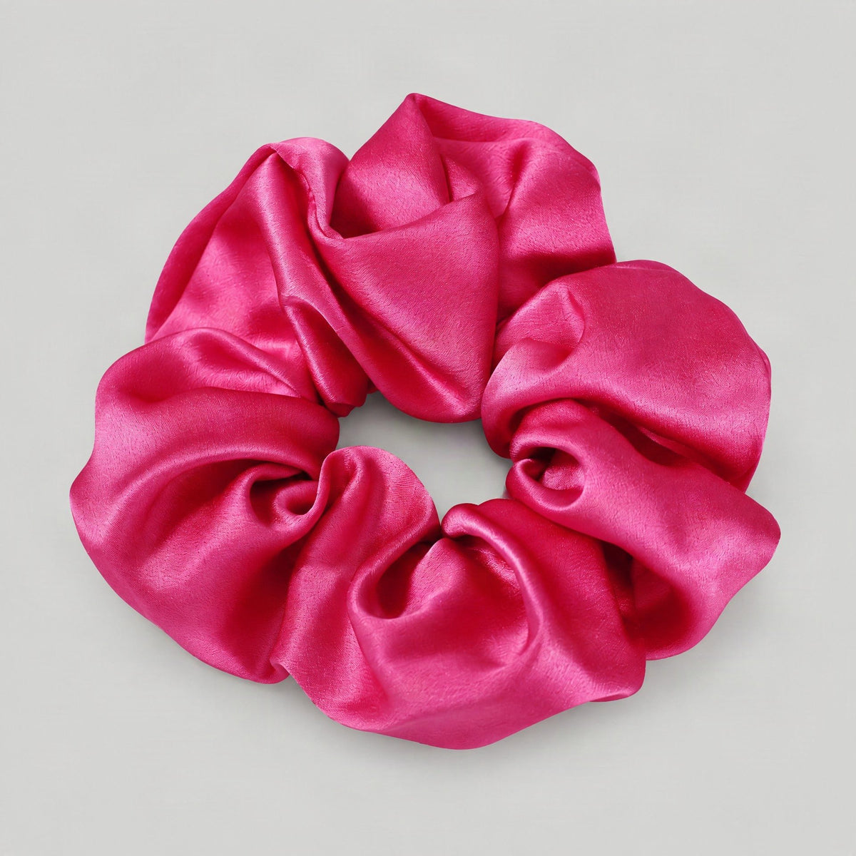 SuuSilk 30 Momme Mulberry Silk Scrunchie in soft pink resting on a marble surface, showcasing its smooth sheen.