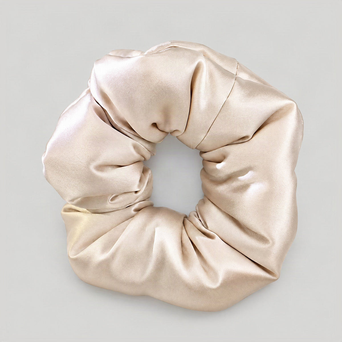 SuuSilk 30 Momme padded mulberry silk scrunchie in soft neutral tone, styled on a marble surface with delicate lighting