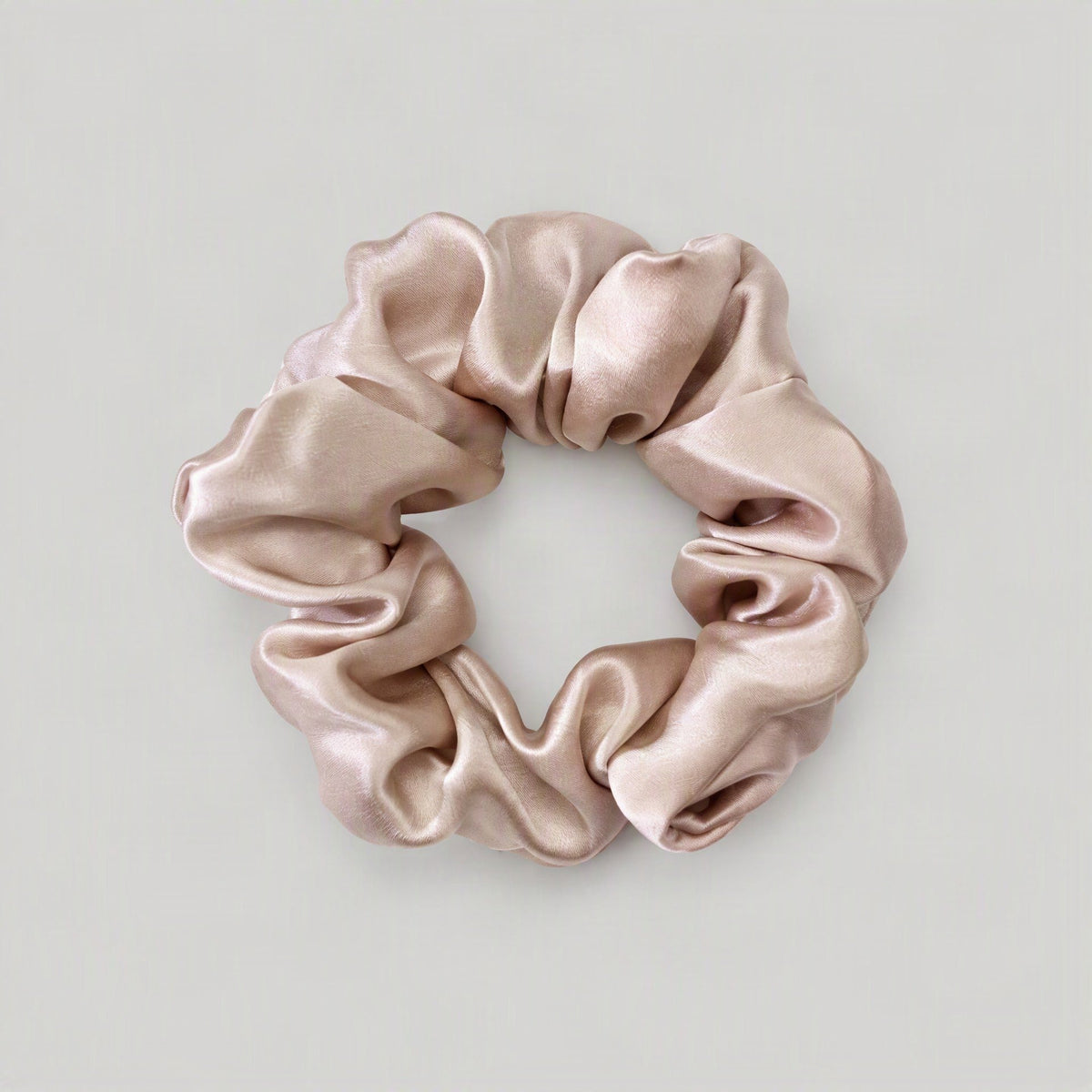 100% Mulberry Silk Scrunchie in soft pink resting on a marble surface, showing its gentle fabric.