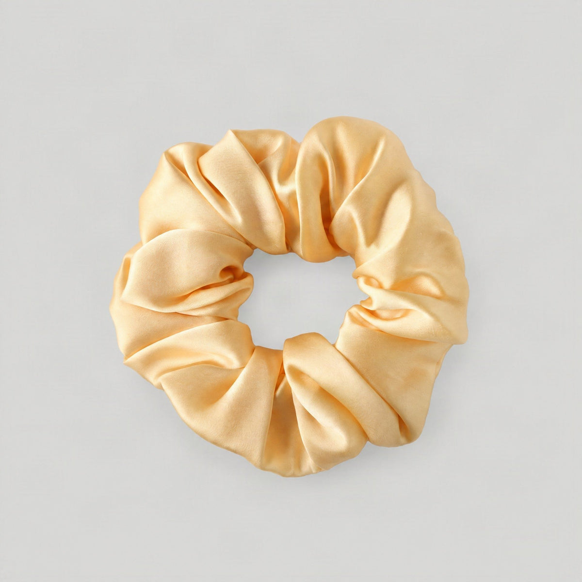 SuuSilk 16 Momme Mulberry Silk Scrunchie in soft blush, ruffled edge draped on a marble vanity surface