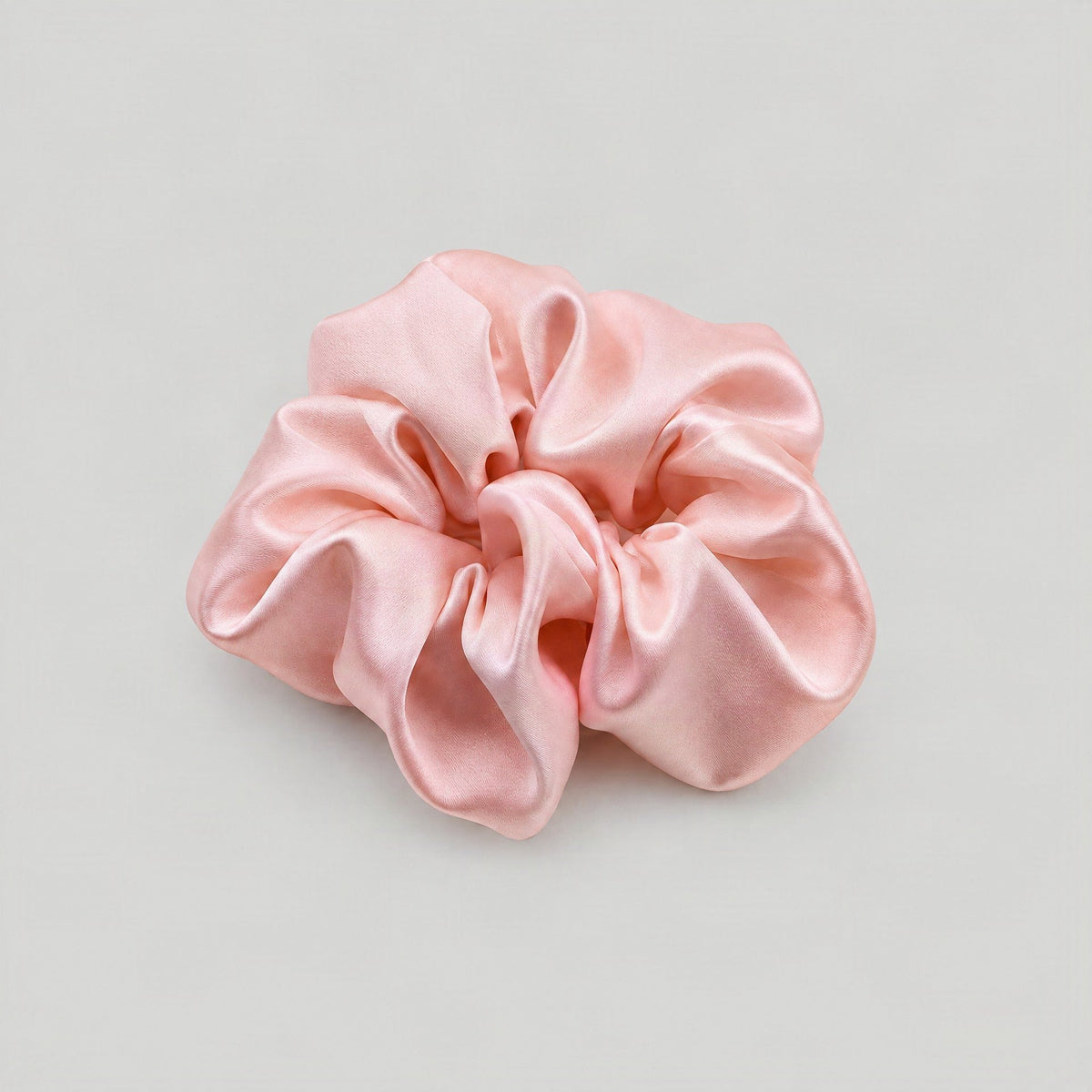 Lustrous champagne-colored 30 Momme mulberry silk scrunchie styled on a marble vanity beside a hairbrush, showcasing its gent
