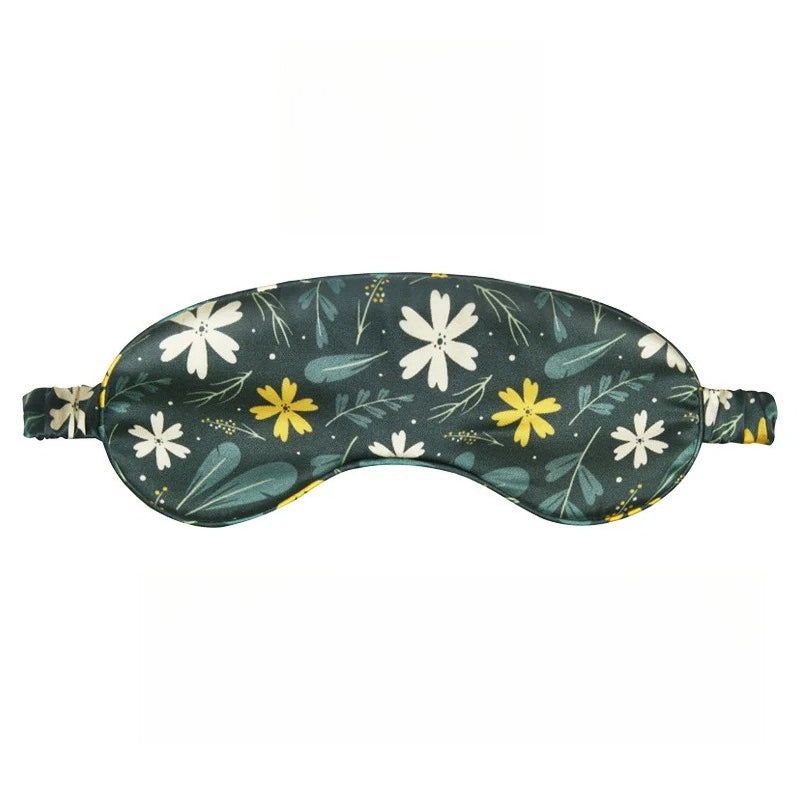 SUUMEE mulberry silk sleep eye mask in soft pastel print, draped on a bedside table beside a book