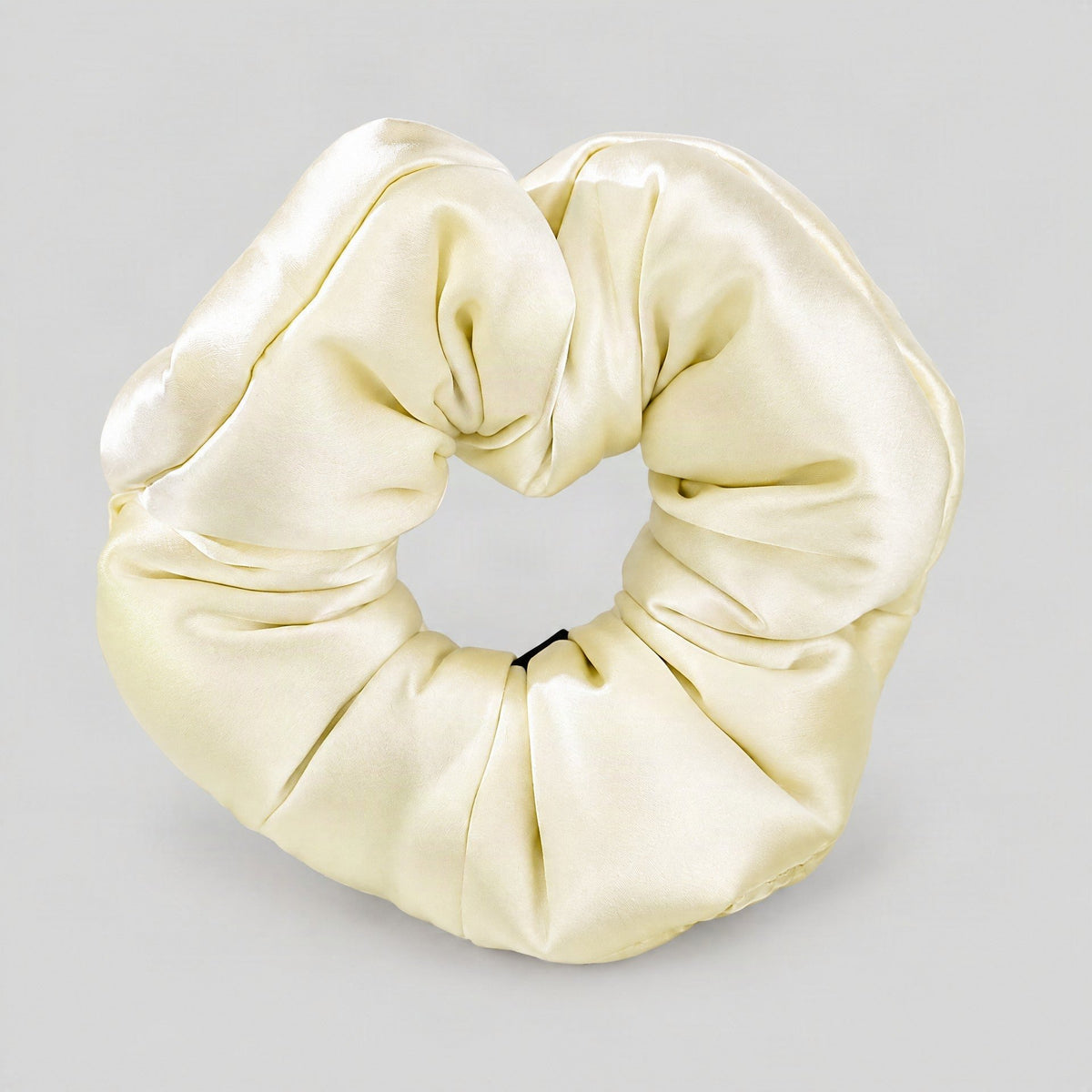 SuuSilk 30 Momme mulberry silk scrunchie in ivory, shown styled on a wrist with soft natural lighting highlighting its plush 