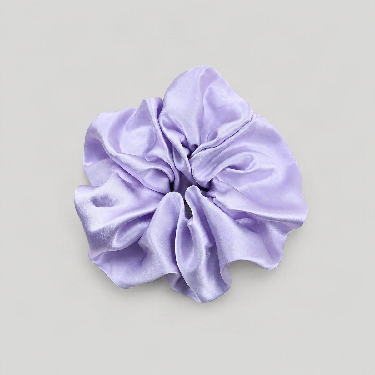 30 Momme mulberry silk scrunchie in soft blush pink, gently wrapped around a loose low ponytail on a marble vanity with natur