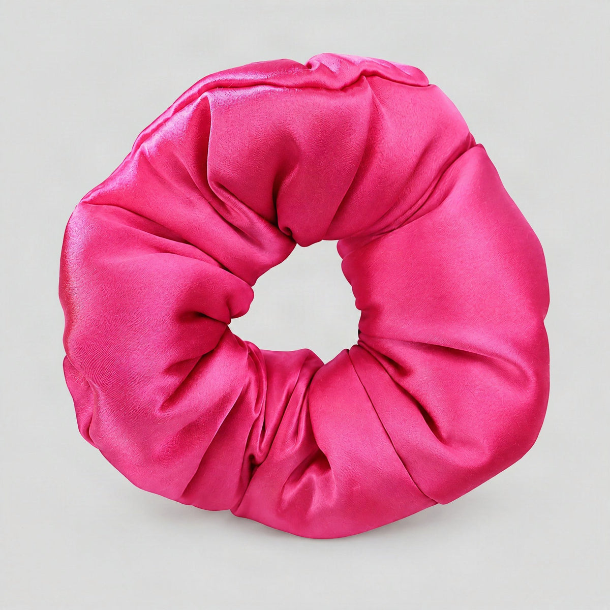 SuuSilk 30 Momme padded mulberry silk scrunchie in cream, resting on a soft beige surface for an elegant everyday look.