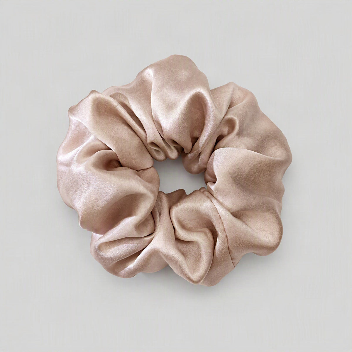 SuuSilk mulberry silk scrunchie in soft blush pink, gently scrunched on a marble surface for everyday hair care.